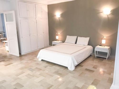1 dormitorio con 1 cama blanca y 2 mesas con lámparas en Cosy apartment @ La marsa Corniche-Beach en La Marsa