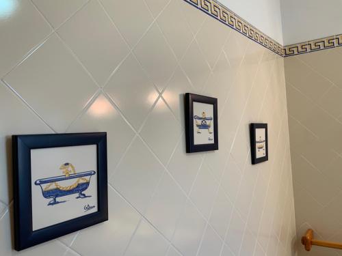 a bathroom with three pictures of a bath tub on the wall at Guest House Alfarrobeiras in Albufeira