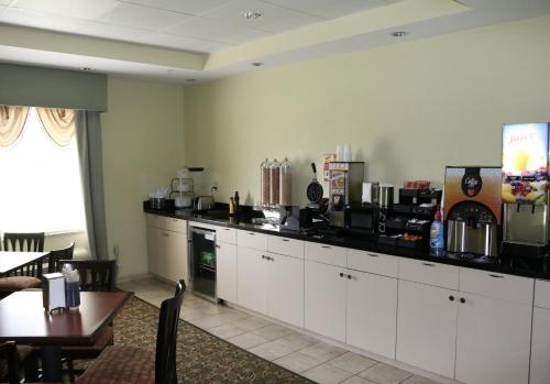 a kitchen with white cabinets and a table and a counter at Ambassador Inn & Suites in Tuscaloosa
