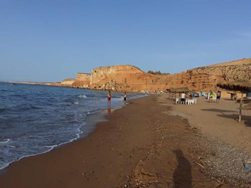 a person standing on a beach next to the water at Dar Hachemia in Ras El Ma