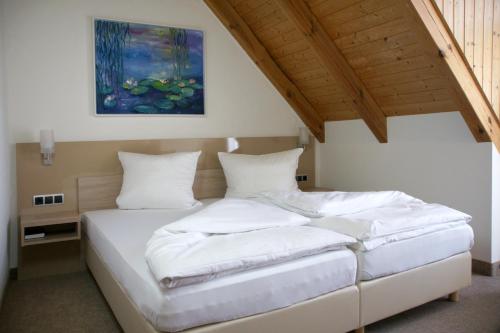 ein Schlafzimmer mit einem Bett mit weißer Bettwäsche und einem Gemälde in der Unterkunft Landgasthof Hotel Rittmayer in Hallerndorf