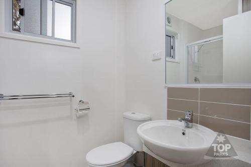 a white bathroom with a toilet and a sink at Horsham Riverside Caravan Park in Horsham