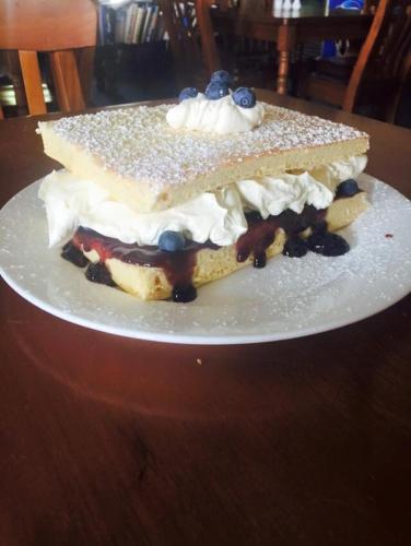 a piece of cake on a white plate on a table at Hill End Lodge in Hill End