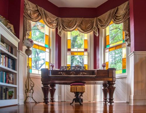 a room with a piano in front of windows at Flowertown Bed and Breakfast in Summerville
