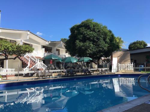 a swimming pool with chairs and umbrellas at Hotel Restaurante Versalles in Melgar