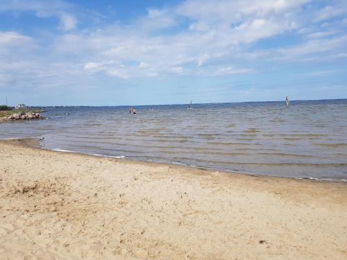 a beach with people swimming in the water at Apartament "Złoty relaks" tuż przy plaży z balkonem z widokiem na Hel i hamakami in Puck