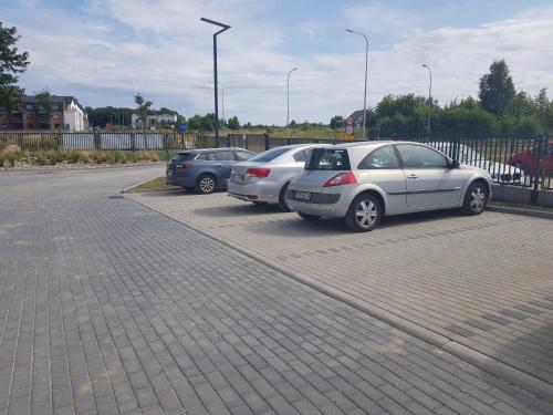 a group of three cars parked in a parking lot at Apartament "Złoty relaks" tuż przy plaży z balkonem z widokiem na Hel i hamakami in Puck