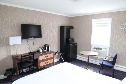 1 dormitorio con 1 cama, escritorio y TV en Walkerton Inn Motel, en Walkerton