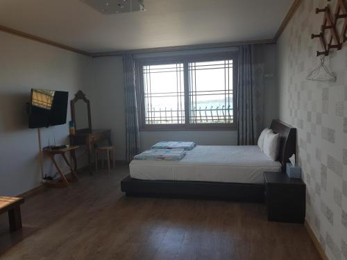 a bedroom with a bed and a large window at Purmir Pension in Seogwipo
