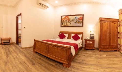 a bedroom with a wooden bed with red pillows at Dragon King 1 Hotel in Da Lat