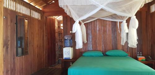 a bedroom with a green bed with a canopy at Sunari Beach Resort 2 in Selayar