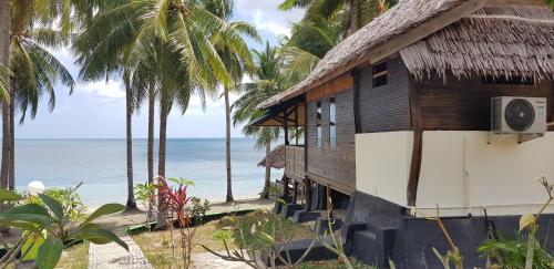 a house on the beach with palm trees at Sunari Beach Resort 2 in Selayar