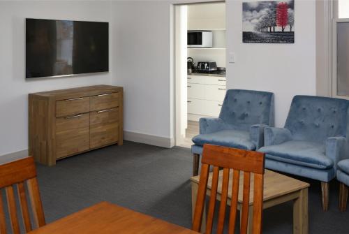 a living room with two chairs and a tv at The Prospect of Howick Accommodation in Auckland