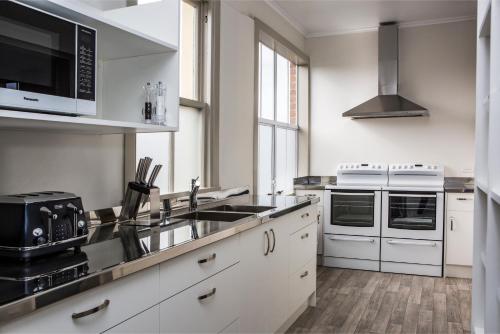 a kitchen with white cabinets and a sink and a microwave at The Prospect of Howick Accommodation in Auckland