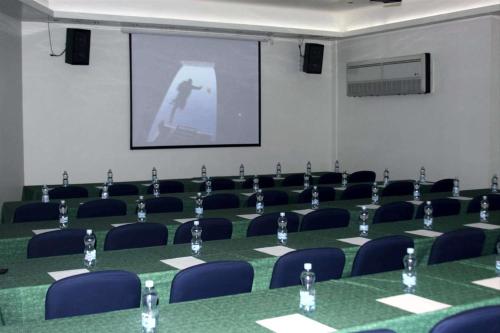 a conference room with tables and chairs and a screen at Hotel Poza Rica Centro in Poza Rica de Hidalgo