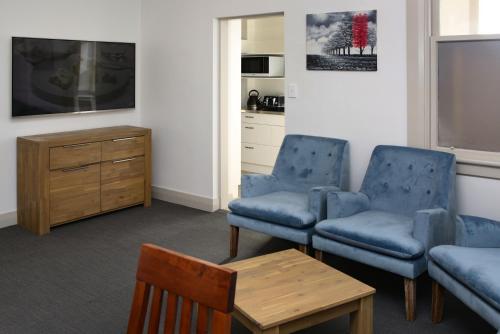 奧克蘭的住宿－The Prospect of Howick Accommodation，客厅配有2把蓝色椅子和桌子