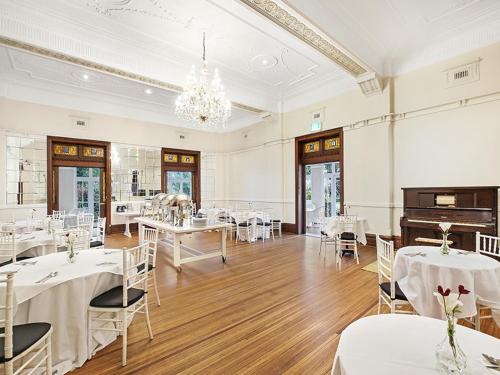 a room with white tables and chairs and a piano at The Robertson Hotel in Robertson
