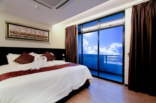 ein Schlafzimmer mit einem Bett und einem großen Fenster in der Unterkunft J Suites Hotel in Kuala Terengganu