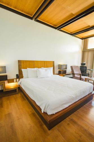 a bedroom with a large white bed and wooden floors at The Park - Silang in Silang