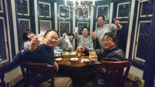 a group of people sitting around a table drinking beer at プチホテル葡萄屋 in Hakuba