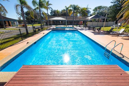 a large swimming pool with a wooden bench in front of it at Seashells Beachfront Resort in Diamond Beach