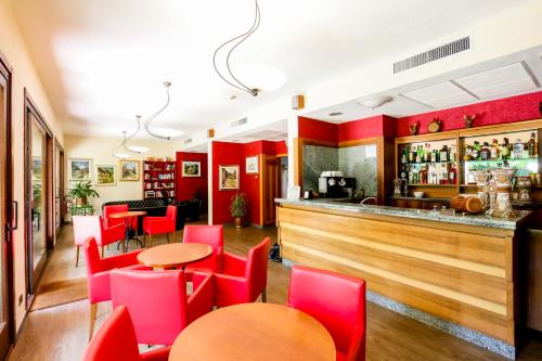 un restaurante con sillas rojas y un bar en Hotel Miage, en Aosta