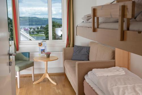 mały pokój z kanapą, łóżkiem i oknem w obiekcie Gjøvik Hovdetun Hostel w mieście Gjøvik