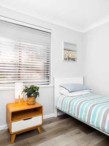 a white bedroom with a bed and a window at Myley's Flat in Forster
