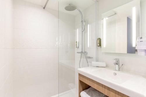 een witte badkamer met een wastafel en een douche bij Best Western Le Beffroi in Loos