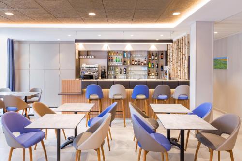 a restaurant with tables and chairs and a bar at Best Western Le Beffroi in Loos