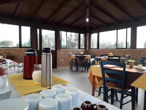 una sala da pranzo con tavoli, sedie e finestre di Agriturismo Quattro Mori a Porto Torres