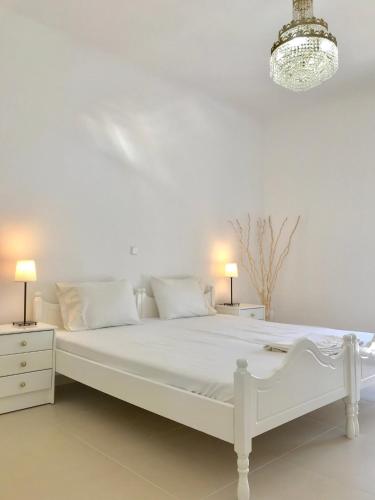 a white bedroom with a white bed and a chandelier at Villa Korais Luxury 3br apt with sea view in Thessaloniki