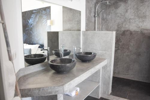 Ninamu Pearl Guest House في بوناويا: ثلاثة أواني على منضدة في الحمام