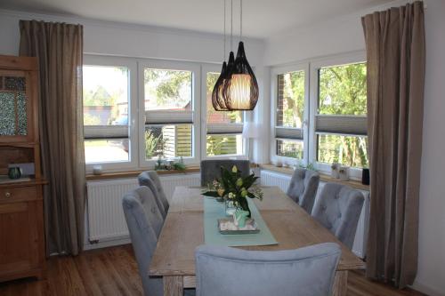 a dining room with a table and chairs and windows at Eulenhaus Osterhever in Osterhever