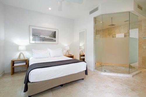 a bedroom with a bed and a glass shower at Allambi Apartment 1, 25 Allambi Rise, Little Cove in Noosa Heads