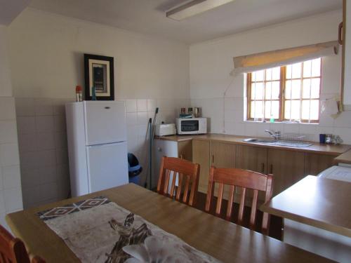 a kitchen with a table and a white refrigerator at Pumula Guest Farm in Fouriesburg