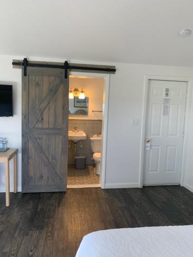 a bathroom with a sliding barn door and a toilet at Cape Motel in Cape Charles