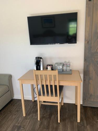 een houten tafel met een stoel en een televisie aan de muur bij Cape Motel in Cape Charles