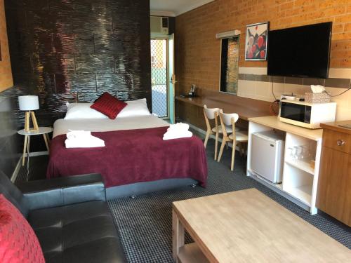 a hotel room with two beds and a tv at Tamworth Central Motel in Tamworth