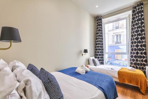 deux lits dans une chambre avec une fenêtre dans l'établissement 94 - Urban French Kiss Montorgueil, à Paris