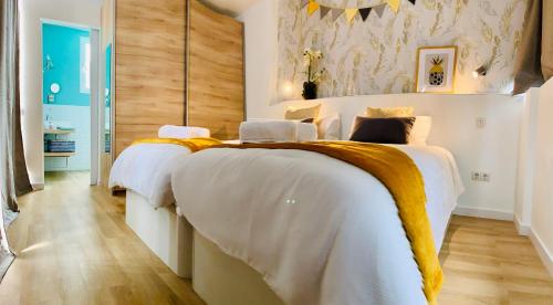1 dormitorio con 2 camas con sábanas blancas y mantas amarillas en Attic Penthouse Downtown Beach 1Gb Fibra, en Las Palmas de Gran Canaria