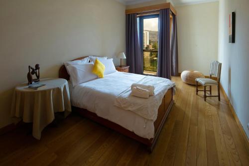a bedroom with a bed with a table and a window at Funchal Bay View Holiday Rental in Funchal