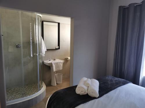 a bathroom with a shower and two towels on a bed at Rosedene in Bloemfontein