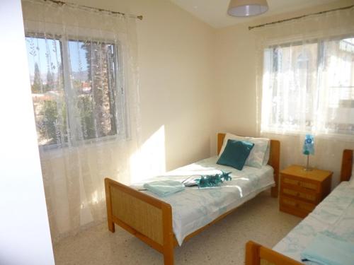 a bedroom with a bed and two windows at Villa Magnolia in Coral Bay