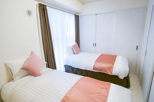 two beds in a room with a window at momo premium 401 in Sapporo