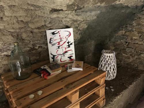 une table en bois avec des livres et une peinture sur celle-ci dans l'établissement ,A cantinella, une cave a fromage au centre corse, à Santa-Lucia-di-Mercurio