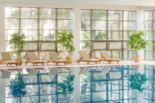 a lobby with a pool and chairs and windows at RODINA Grand Hotel & SPA in Sochi