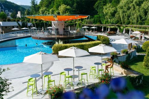 een zwembad met groene stoelen, tafels en parasols bij Apartament Hotel by Derenivska Kupil in Nyzhne Solotvyno