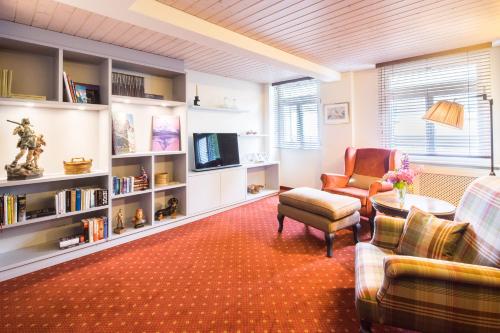 a living room with a couch and chairs and a tv at Hotel Kreuz & Post Grindelwald in Grindelwald
