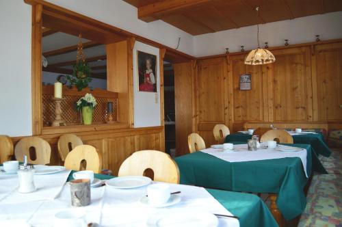 a dining room with two tables and chairs and a chandelier at Pension Leitenhof in Niederau